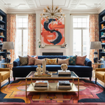 Living room with a blue sofa, colorful rug, and abstract painting on the wall.