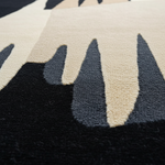 Close-up of a textured rug with black, beige, and gray pattern