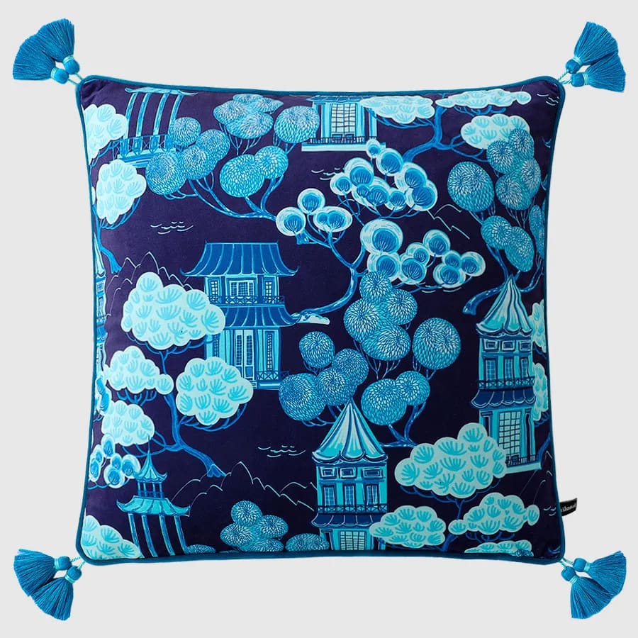 Celestial Chinoiserie throw pillow featuring vibrant blue and white pagoda and tree designs on a navy background, accented with decorative tassels.