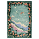 A vibrant hand-tufted wool area rug featuring an abstract design with a tiger floating among clouds, surrounded by colorful floral borders and mountainous landscapes. The Celestial Drift rug adds a whimsical touch to any room.