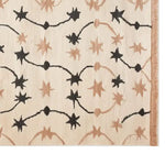 Top view of the Celestial Rhapsody Knotted Wool Rug, featuring a striking abstract star pattern in black and beige on a cream background. This area rug adds a touch of elegance and modern design to any space.