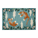 Vibrant area rug featuring playful tigers in an abstract design, surrounded by floral and leaf patterns on a teal background.