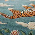 Close-up of a tiger rug on a blue background with flowers and clouds.