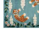 A beautifully crafted hand-tufted wool area rug featuring a vibrant abstract tiger design. The rug displays a playful tiger amidst floral patterns on a soothing blue background, perfect for adding a touch of elegance and whimsy to any room.