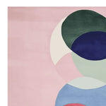 The Chakra Circle Dance Hand Tufted Rug showcases an abstract design with overlapping circles in shades of pink, green, blue, and white. This area rug, made from high-quality wool, is a perfect square, adding a contemporary touch to any living room.