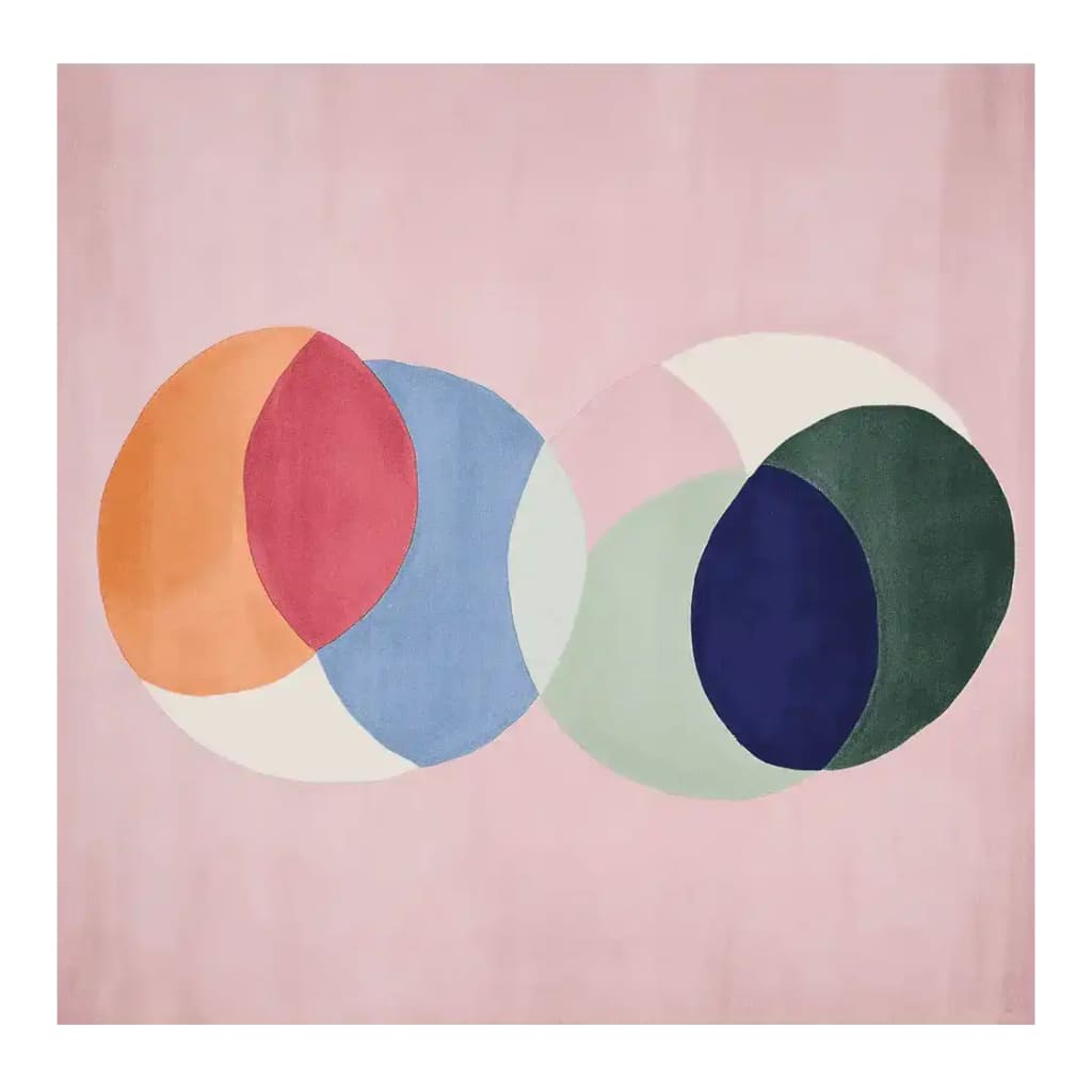 Chakra Circle Dance Hand Tufted Rug showcasing a vibrant design with overlapping circular patterns in orange, red, blue, green, and white on a soft pink background. This contemporary wool rug is perfect as a square area rug for living room spaces, adding a touch of modern elegance.