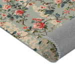 Rolled chinoiserie charm rug close-up, detailed pink roses and bird print with gray backing visible