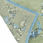 Close-up of a floral-patterned rug with blue and white flowers on a green background