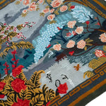 The Chinoiserie Vista Hand Tufted Rug showcases a vibrant floral design with intricate patterns in shades of blue, red, and gold. This large area rug is perfect for a living room, offering a luxurious wool texture and square shape that enhances any space with its elegant artwork.