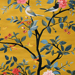 Vibrant hand-tufted area rug depicting a cherry tree with detailed birds and flowers on a rich golden background, showcasing intricate artistry and vivid colors.