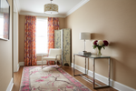 Living room with floral rug, armchair, side table, and decorative elements.