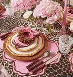 pink scalloped Cinnamon Swirl placemat at glam table with leopard cloth, rattan charger and pink hydrangeas