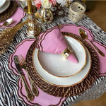 Cinnamon Swirl placemat pink with brown scalloped edge on zebra tablecloth, gold cutlery and rattan charger