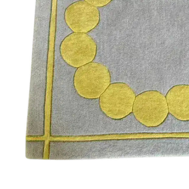 Close-up view of the Circle of Suns Square Hand Tufted Wool Rug in gray, showcasing its contemporary design with a pattern of yellow circles. This square area rug is perfect for adding a modern touch to any bedroom setting.