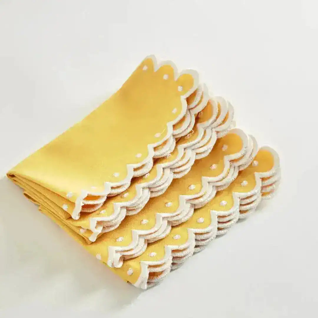 Citrus Glow placemats folded and stacked showing yellow linen with white scalloped eyelet edge, side detail