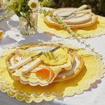 yellow round scalloped Citrus Glow placemat with white eyelet edge, bamboo charger and yellow napkin, garden
