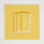 Citrus Glow placemat square flat lay, yellow with white scalloped eyelet border and folded yellow napkin