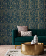 Cityscape glam wallpaper with gold Art Deco geometric lines on navy behind a teal tufted sofa and gold drum coffee table