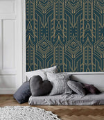 Cityscape glam wallpaper with gold geometric motifs on navy as accent panel beside a white molded wall, gray floor sofa