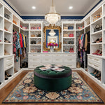 Luxurious walk-in closet with white shelves, a blue traditional floral wool rug, clothing, and decorative elements.