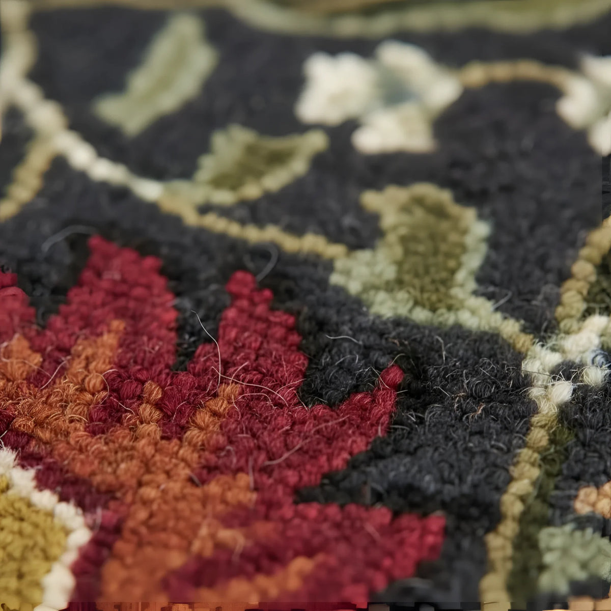 Close-up of a textured rug with autumn leaf pattern in red, orange, and green on a dark background.