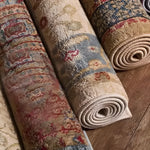 A close-up view of rolled Classic Maia Traditional Printed Area Rugs, showcasing intricate patterns in warm tones. Ideal for adding a touch of elegance to living rooms or offices, these area rugs blend traditional design with modern style.