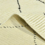 Close-up view of a Classic Moroccan Hand Spun Wool Hand Knotted Area Rug showcasing intricate black line patterns on a cream background. Ideal for adding a touch of elegance to living room area rugs, perfect in an 8x10 size.
