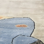 Close-up of a textured rug with a blue abstract design on a beige background