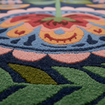 Close-up of Mexican Fiesta rug pile, navy ground with coral, orange and red floral medallion