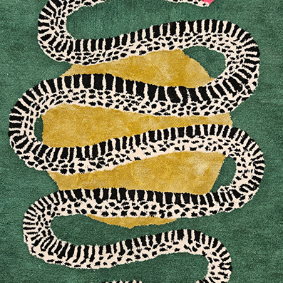 Close-up of the patterned snake coiling across gold and green wool on the scalloped rug