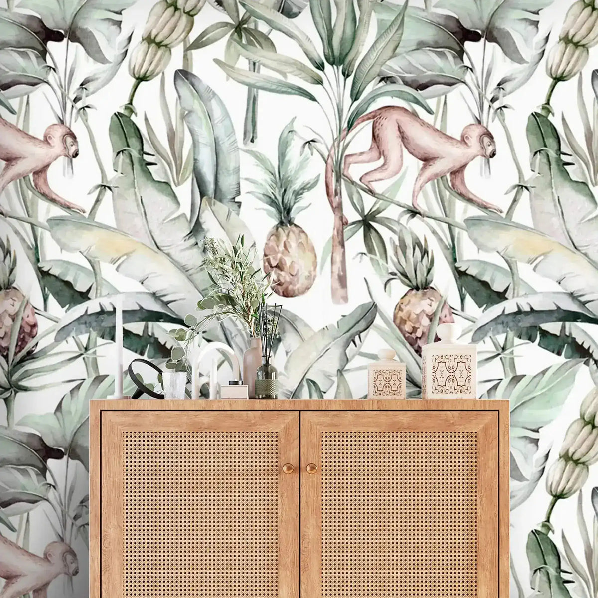 Close-up watercolor tropical jungle wallpaper with monkeys and pineapples behind cane rattan cabinet