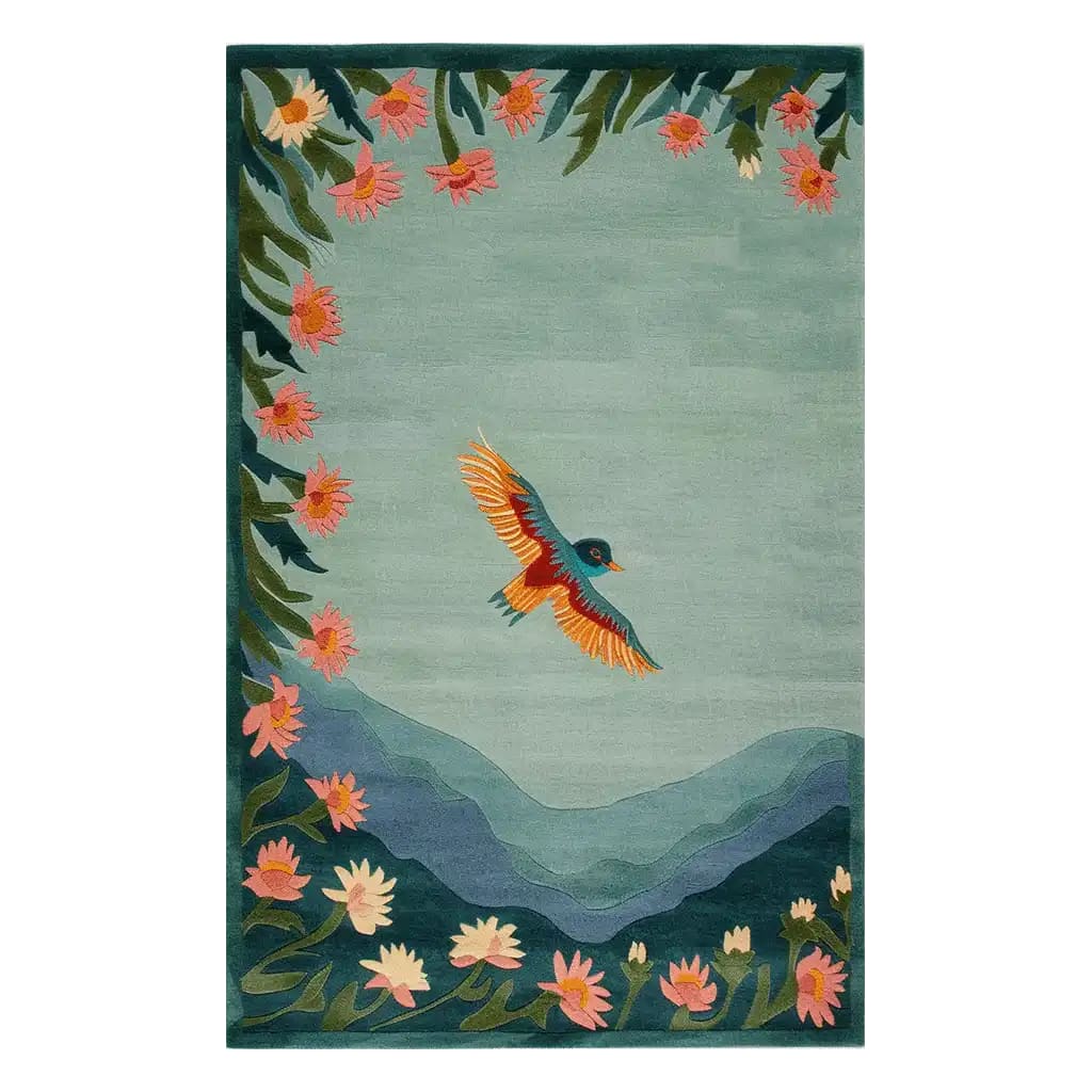 The Cloudsong Flight Hand Tufted Wool Area Rug features an artistic design of a vibrant bird soaring over stylized mountains and surrounded by colorful flowers. This elegant wool rug brings a touch of nature and tranquility to any room.