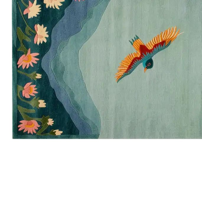 A beautifully designed area rug showcasing a bird in flight over a serene blue background, complemented by a border of pink and white flowers. The intricate hand-tufted wool pattern adds elegance and charm to any room.