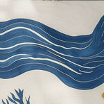 Close-up of the Coastal Calm Hand Tufted Wool Area Rug featuring a wave-like blue abstract design on a light background.