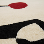 Close-up of a geometric patterned rug with red, black, and white colors.