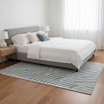 Bedroom with a neatly made bed, striped rug, and wooden side table.