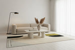Modern living room with a beige sofa, minimalistic wool rug, coffee table, and decorative elements.