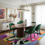 Dining room with a wooden table, green chairs, colorful rug, and abstract art on the wall.