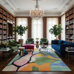 Luxurious living room with a colorful rug, green chairs, and a blue sofa.