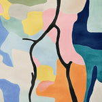 This vibrant area rug showcases an abstract design with bold, colorful blocks in pink, yellow, blue, and green, intersected by striking black lines. Perfect for adding a contemporary touch to any living room, this hand-tufted wool rug combines style and comfort, making it an ideal choice for those seeking modern area rugs for living room spaces.