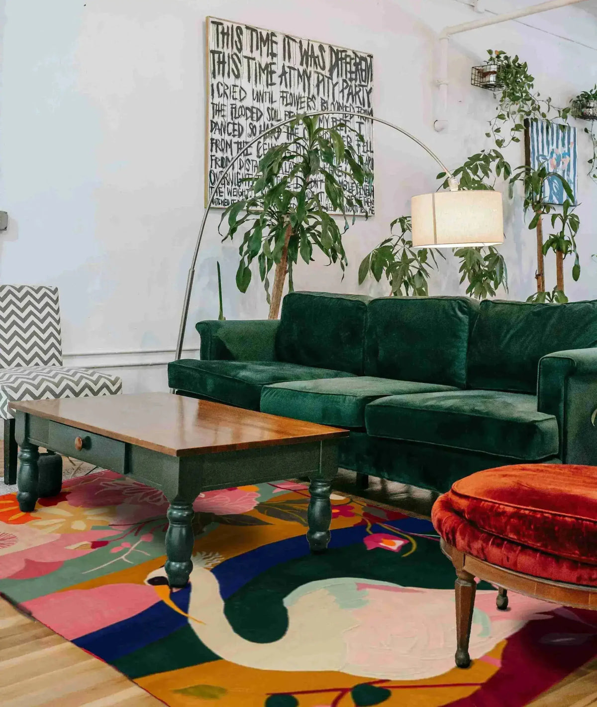A vibrant and colorful hand tufted area rug featuring a swan design, perfectly complementing a stylish living room setup. The wool rug adds warmth and character, with a green velvet sofa, wooden coffee table, and chic decor. Ideal for those seeking large area rugs for living room enhancement.