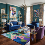 Modern living room with blue sofa, purple armchair, and colorful rug.