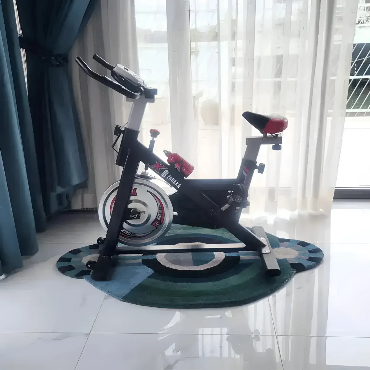 A stylish and contemporary round evil eye hand-tufted wool rug placed under a stationary bike in a bright room. The area rug showcases a vibrant design, perfect for enhancing bedroom decor. Ideal for those seeking large bedroom area rugs or a cozy wool rug to add warmth and style.