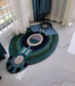 A contemporary round evil eye hand-tufted wool rug in rich shades of blue and green, perfect for adding a modern touch to bedroom décor. This stylish area rug is designed to fit beautifully as a bedroom area rug, offering a cozy and inviting feel. Ideal for those seeking large area rugs with a unique design.