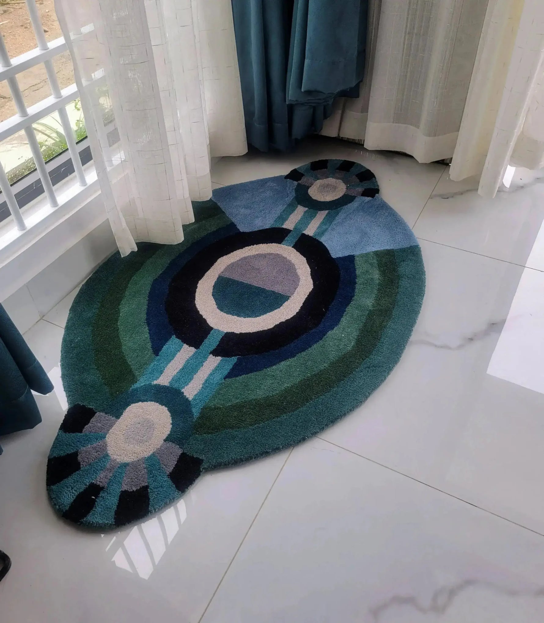 A contemporary round evil eye hand-tufted wool rug in rich shades of blue and green, perfect for adding a modern touch to bedroom décor. This stylish area rug is designed to fit beautifully as a bedroom area rug, offering a cozy and inviting feel. Ideal for those seeking large area rugs with a unique design.