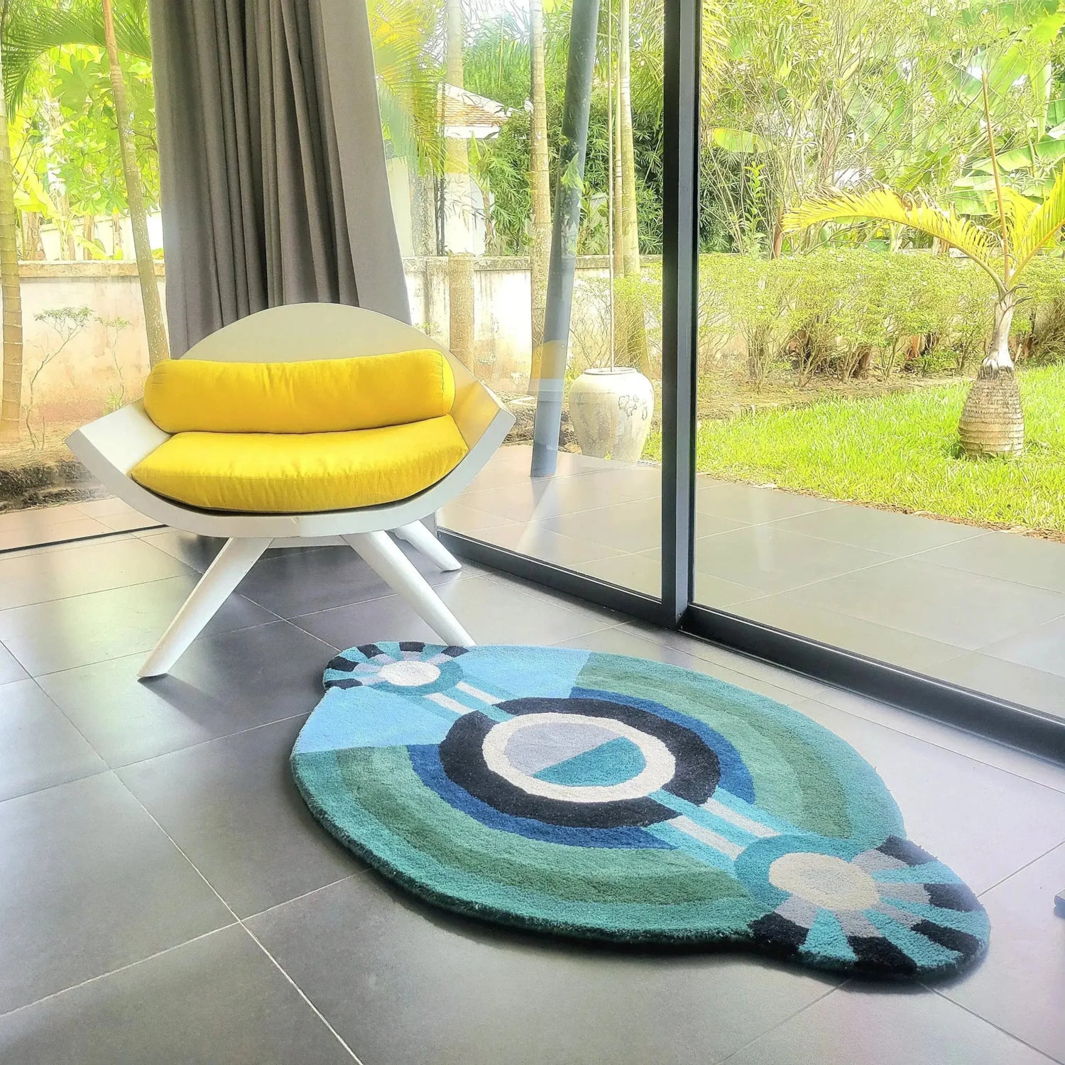 Modern living room featuring a Contemporary Round Evil Eye Hand Tufted Wool Rug. This stylish area rug adds a touch of elegance to the room's sleek gray tiles, ideal for enhancing bedroom decor with its unique design. Perfect for those seeking large area rugs crafted from high-quality wool.
