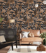 Copper palm tree wallpaper on navy in a living room with tan sofa, black cabinet and globe lamps
