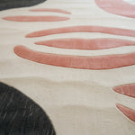 Close-up of a textured rug with pink and black patterns on a beige background