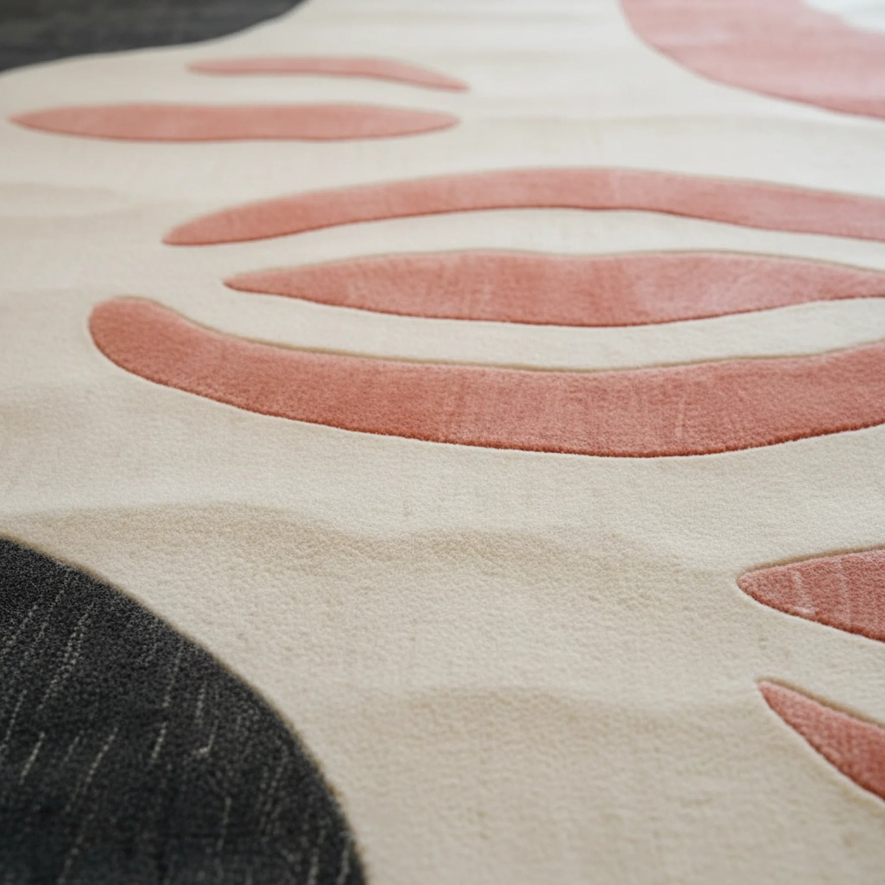 Close-up of a textured rug with pink and black patterns on a beige background