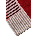 Corner close-up of the retro door rug, striped grey, blush and burgundy tufted pile